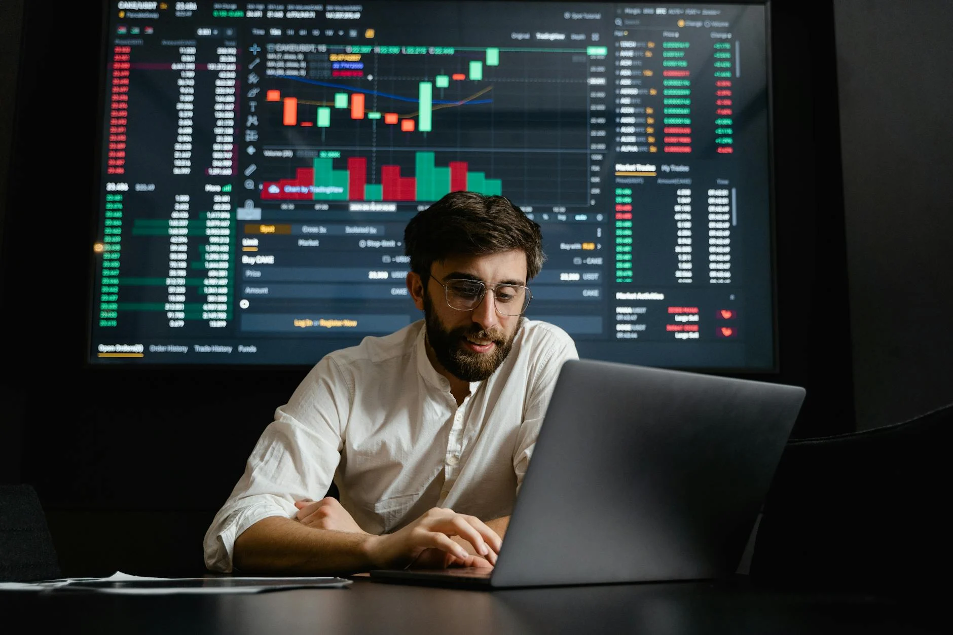 Male analyst studies cryptocurrency trends at a workstation with multiple displays showing market data.